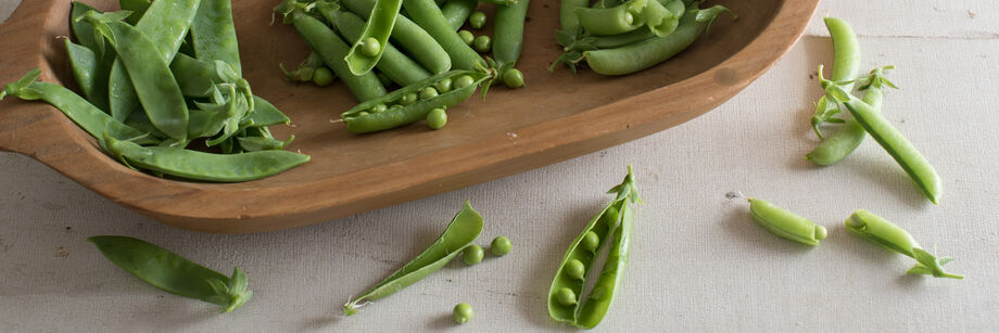 Snow, shell, and snap pea varieties displayed in a wooden dish.